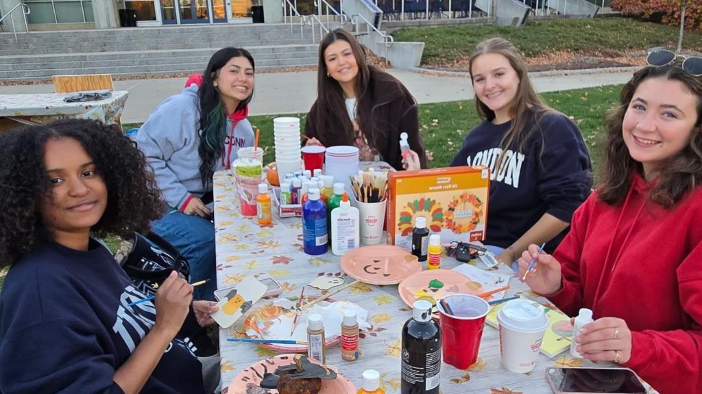 A group of students working on arts and crafts at a table outside.