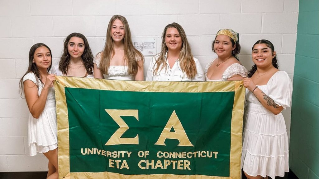 Members of the Sigma Alpha sorority hold up a banner during formal.