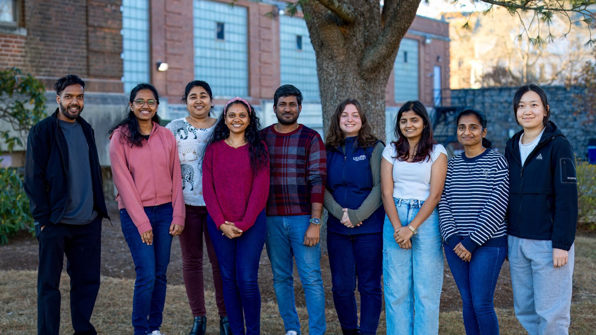 A group of individuals posing for a photo outside on a sunny day